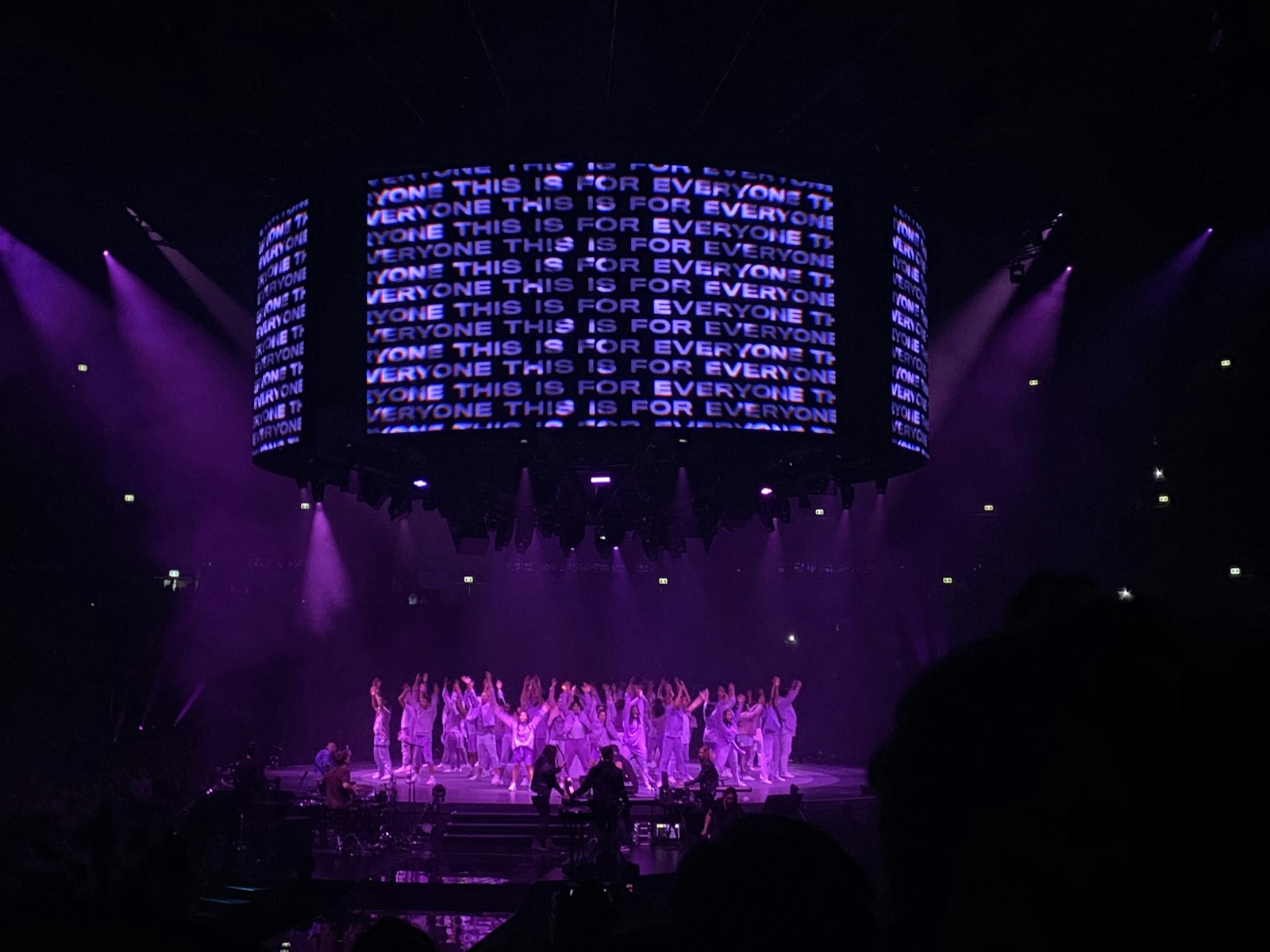 Pantalla LED circular con texto iluminado sobre un escenario, mostrando claramente una gran pantalla de LEDs en un evento en vivo